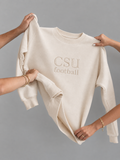 A cream-colored crewneck sweatshirt with 'CSU football' embroidered on the chest, held up by multiple hands against a solid gray background.