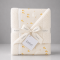 A folded Kadori baby blanket with a sherpa fleece border and a printed cream fabric center featuring a white goose and small yellow duck motifs. The blanket is wrapped in a cream ribbon printed with the Kadori brand name and tied with a white paper tag.