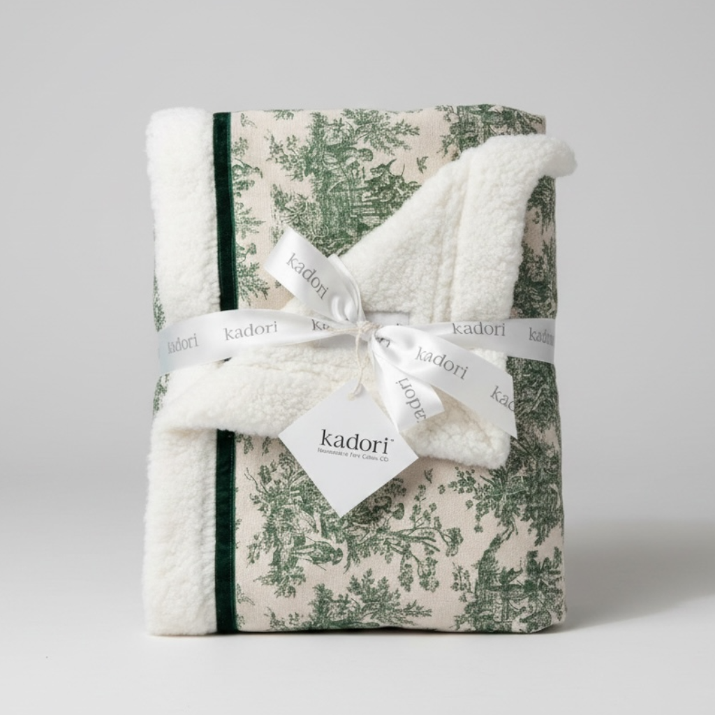Folded blanket with floral pattern and white border, tied with a ribbon and 'kadori' label on a light gray background.