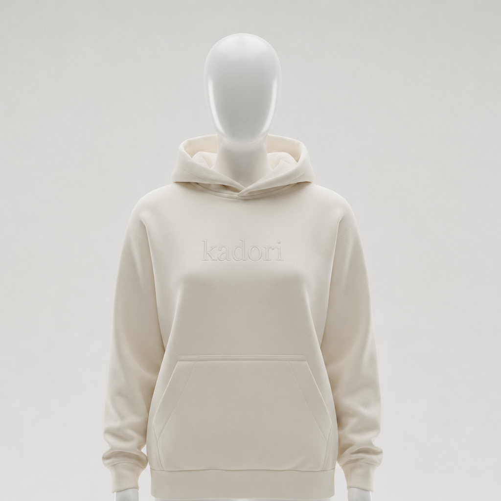 An off-white pullover hoodie displayed on a white mannequin against a light gray studio background. The hoodie features the brand name 'kadori' embroidered in tonal off-white lettering across the chest.