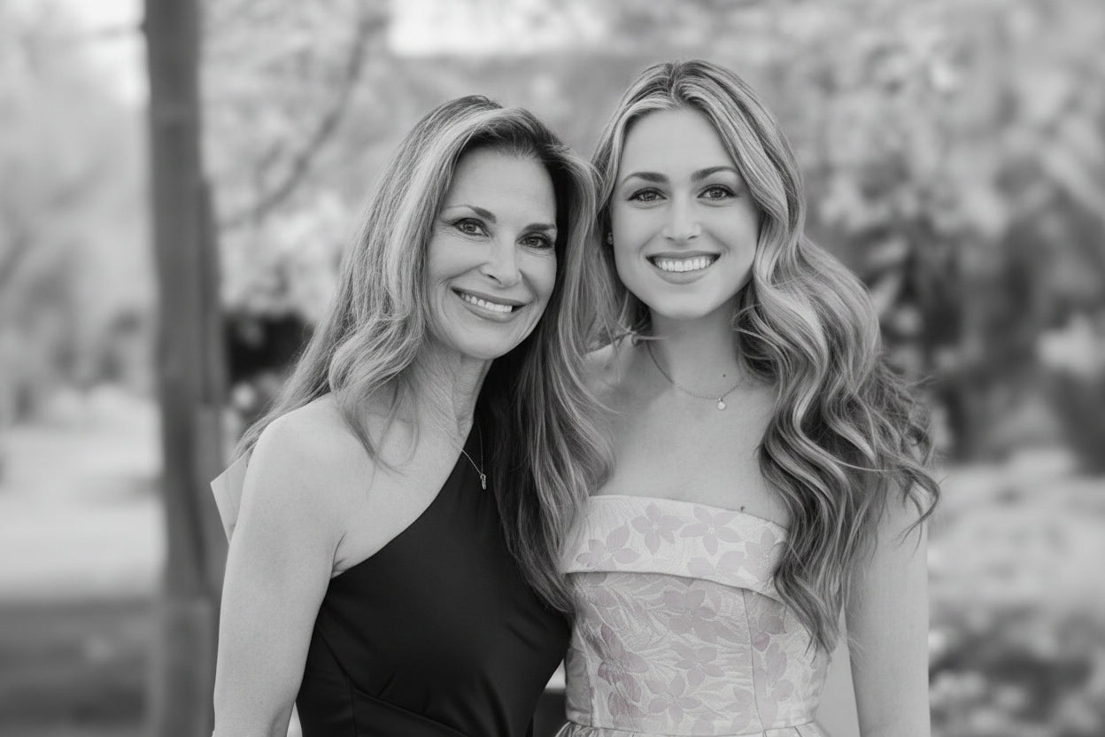 Two women posing together outdoors with trees in the background